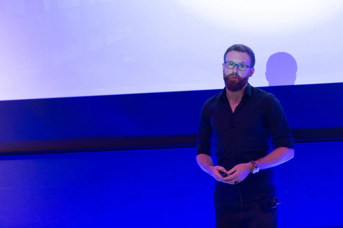 Max Frenzel on stage giving a talk in front of a projection screen